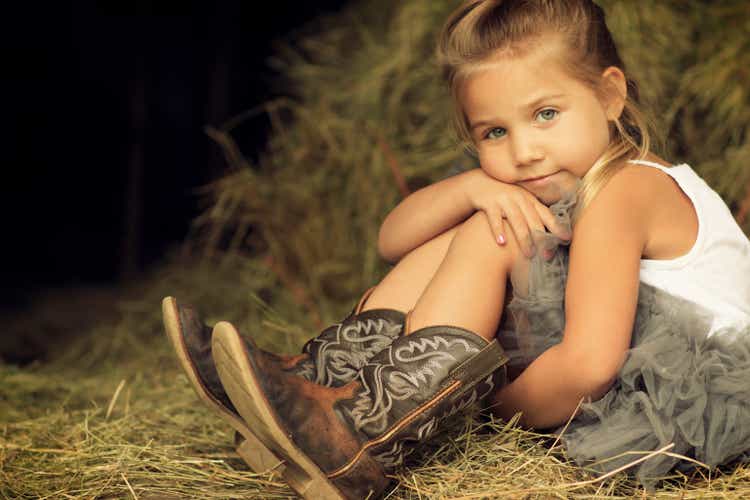Blonde little girl sitting in hay