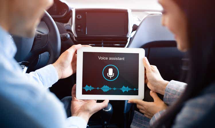 Couple using voice assistant on tablet sitting in car, back-view