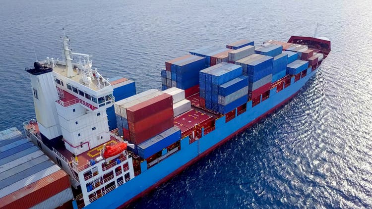 ULCV container ship sails on open water fully loaded with containers and cargo.