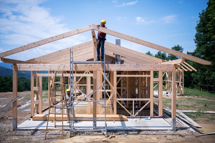 Construction Workers Working On Wooden Roof Of House.