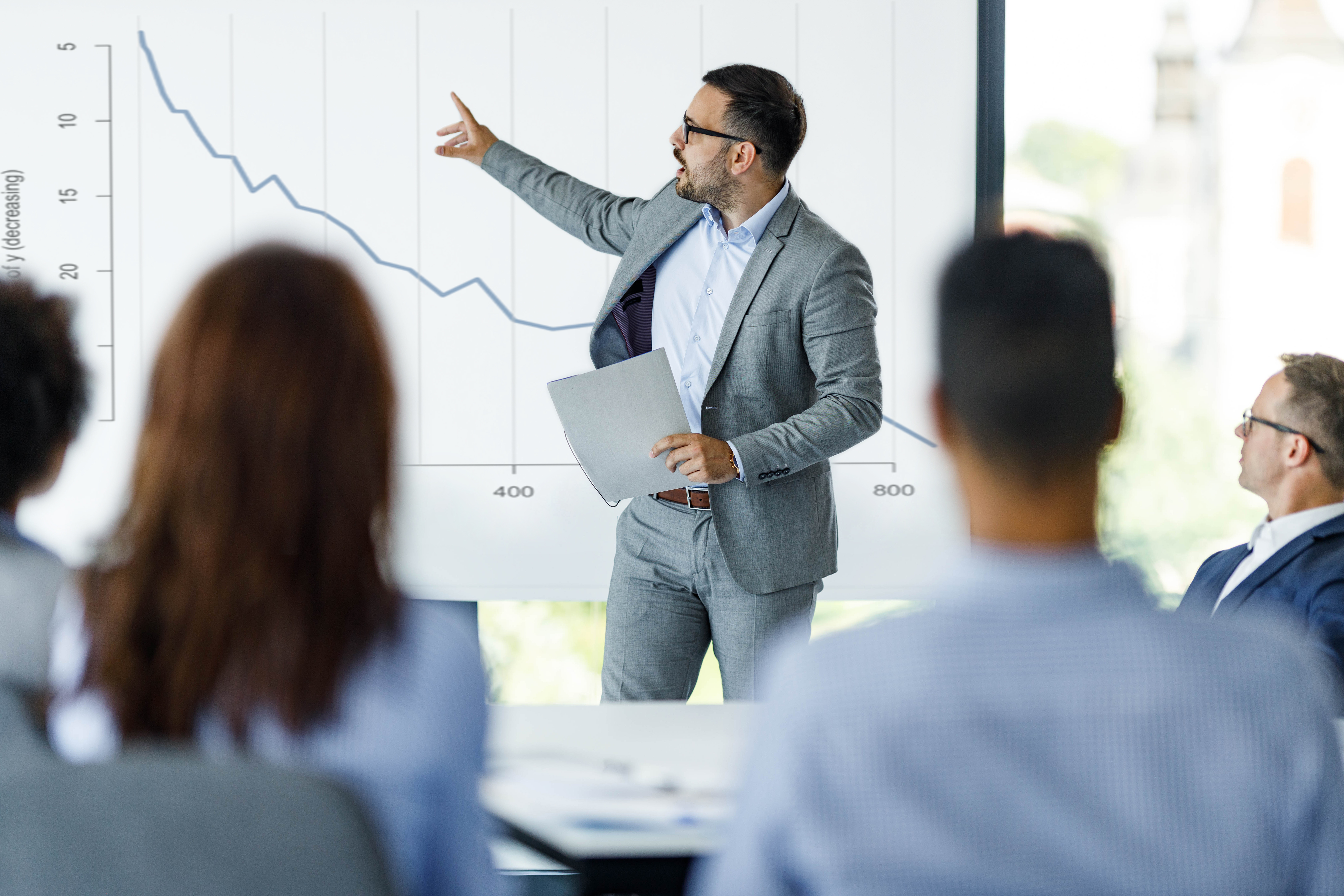 Male CEO talking about economic crisis on presentation in the office.