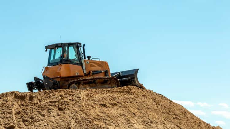 a bulldozer on a large pile of sand against a blue sky