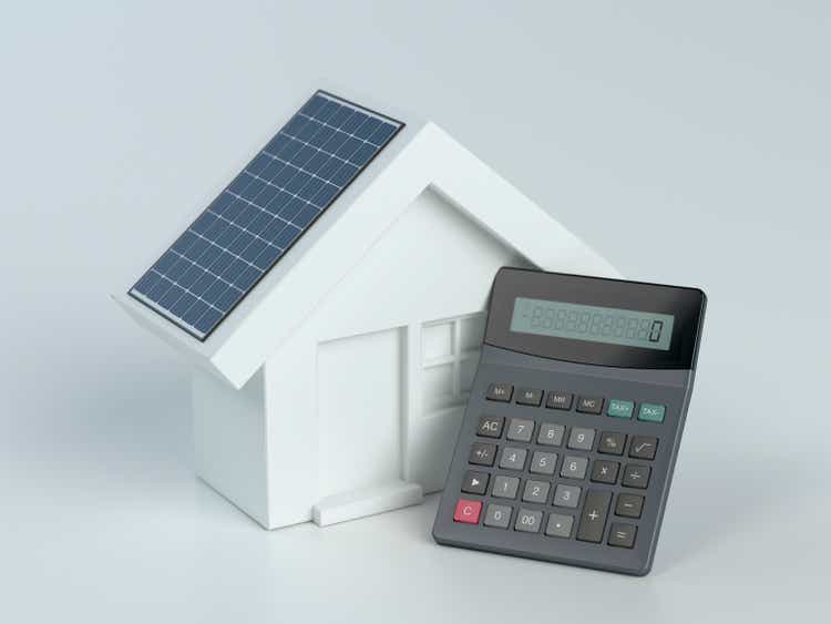 House with photovoltaic solar panel and calculator on white background