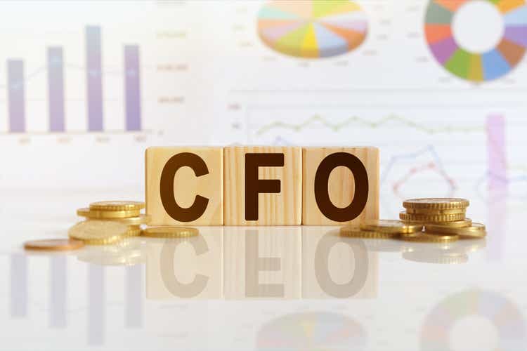 CFO the word on wooden cubes, cubes stand on a reflective surface, in the background is a business diagram.