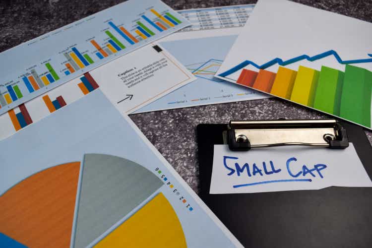 A small cap writes on a sticky note isolated on the office desk.stock market concept