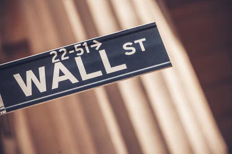 The Wall Street sign in New York City with the New York Stock Exchange in the background