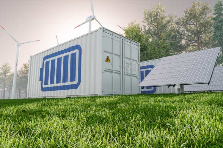 Solar panel, wind turbines and lithium ion battery container with blue sky background. Energy storage system.