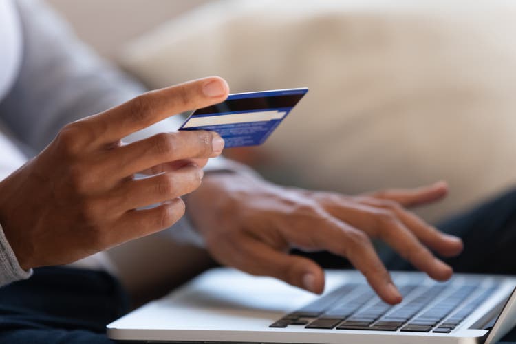 Close up of girl hold bank card and type on laptop