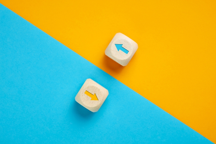 Pfeil-Symbole im Gegensatz zu Holzwürfeln, die sich in entgegengesetzte Richtungen bewegen. Wettbewerb, Vielfalt, Opposition oder Konfrontationskonzept.