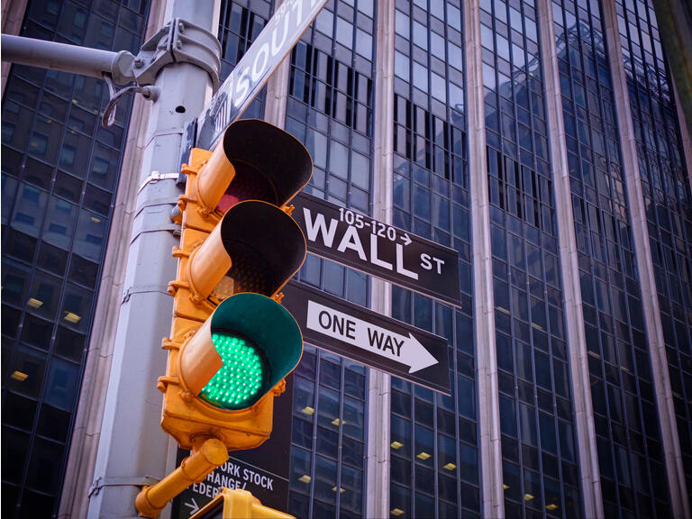 View on wall street yellow traffic light with black and white pointer guide. Green traffic light to Wall street banks money dollars finance offices. New York traffic light on Wall street money