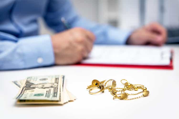 Businessman in the back, us dollars and gold jewellry in the front, disposal and selling