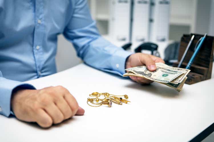 Man buying golden jewellry, pawn shop and america dollar banknotes
