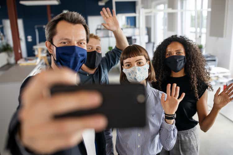 People with face masks back at work taking selfie