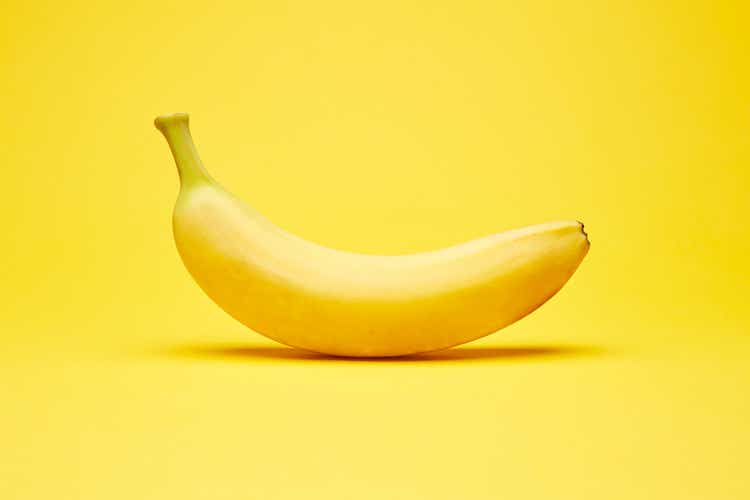 Enige verse ruwe schone geïsoleerde één alleen horizontaal georiënteerde gele banaan op de heldere stevige gele fondachtergrond