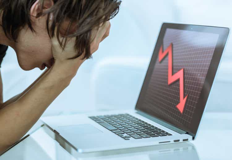 Sad investor watching the financial stock market crash on his laptop computer. Economy crisis.