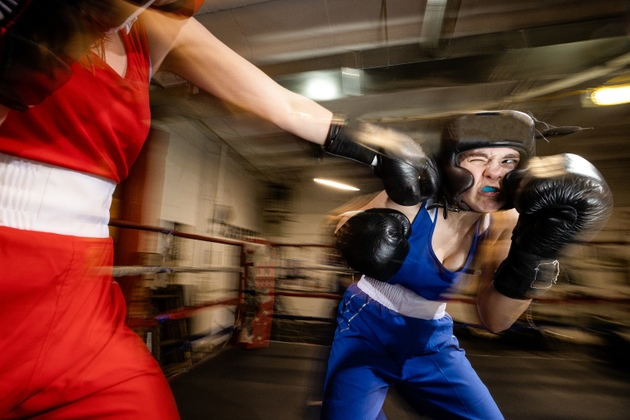 Female boxer getting hit on the chin during a sparring session.