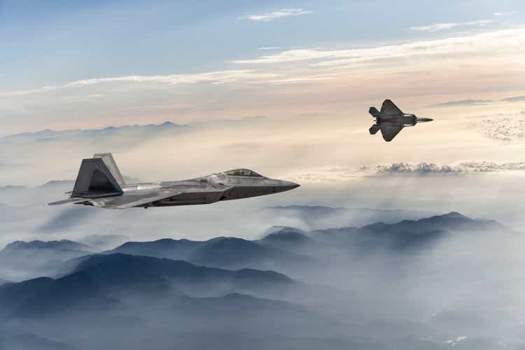 F-22 Stealth Jet Fighters fliegen bei Sonnenuntergang über nebelverhangenen Bergen