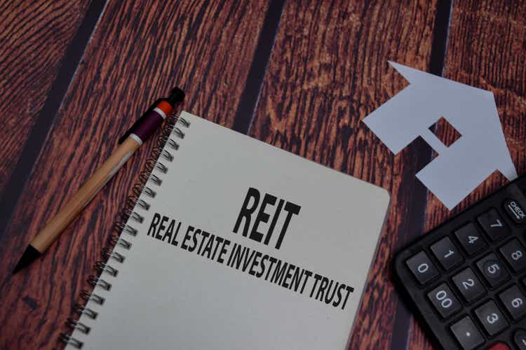 Book about REIT - Real Estate Investment Trust isolated on wooden table.