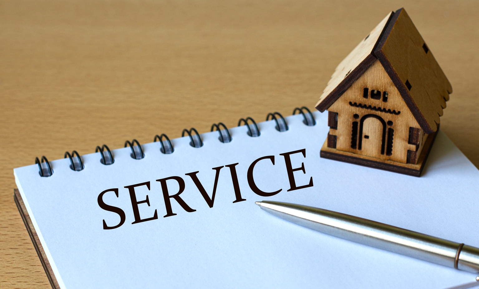 SERVICE - the word is written in a notebook with a pen and a wooden house