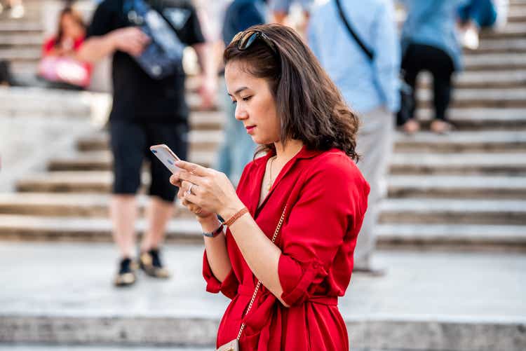 Famous Spanish Steps on summer day and closeup of young tourist woman in red dress looking at phone