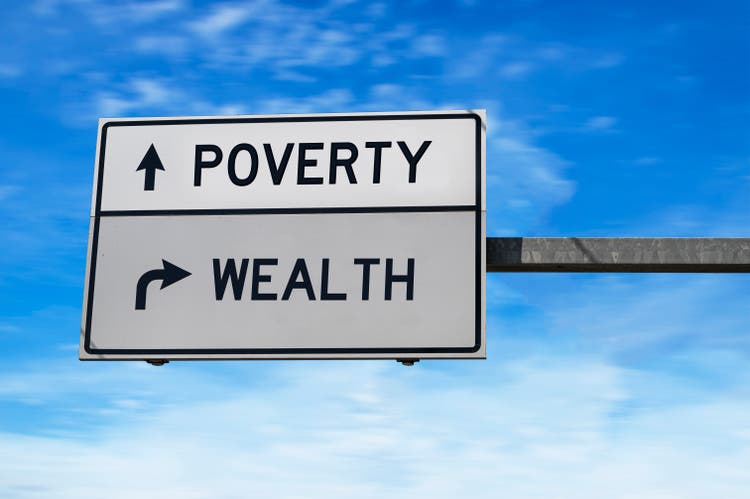 Poverty versus wealth white arrow road sign on blue sky background.