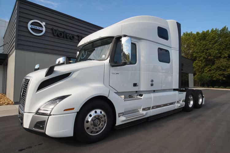 A new white Volvo truck near the car dealership.