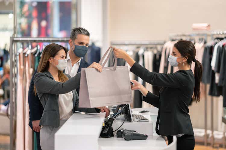 Couple shopping at a clothing store and using facemasks during the pandemic