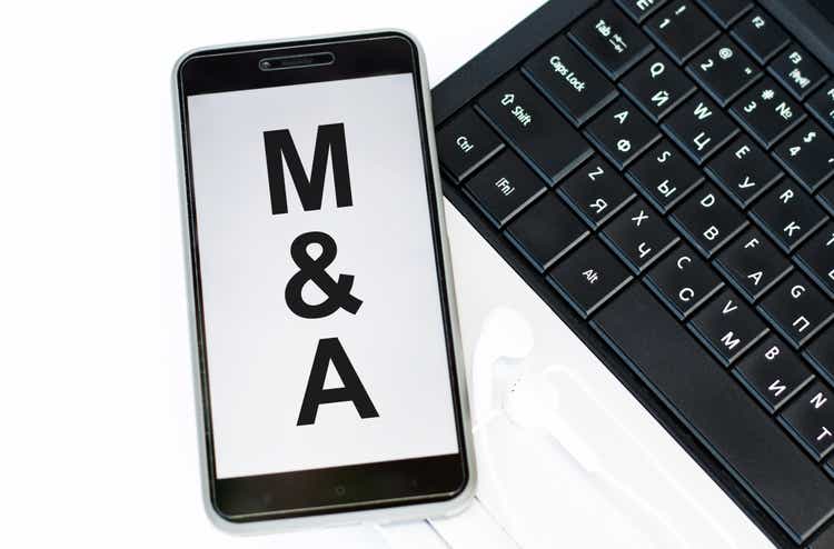 M and A text on the phone, which is on the laptop keyboard. Business concept
