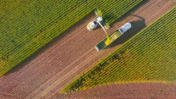 Farm machines, combine and semi-truck harvesting corn
