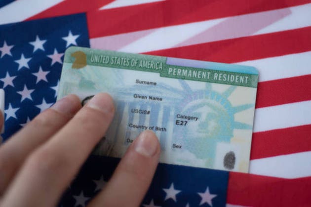 Permanent Resident Green card of United states of America on flag of USA. Above close up view.