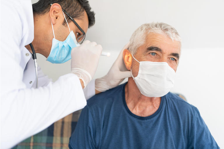 Health worker examine ear of senior man in his house