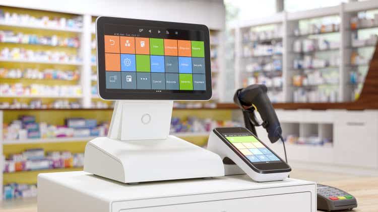 Cash Register On Wooden Table In Pharmacy With Blurred Medicine Shelves Background