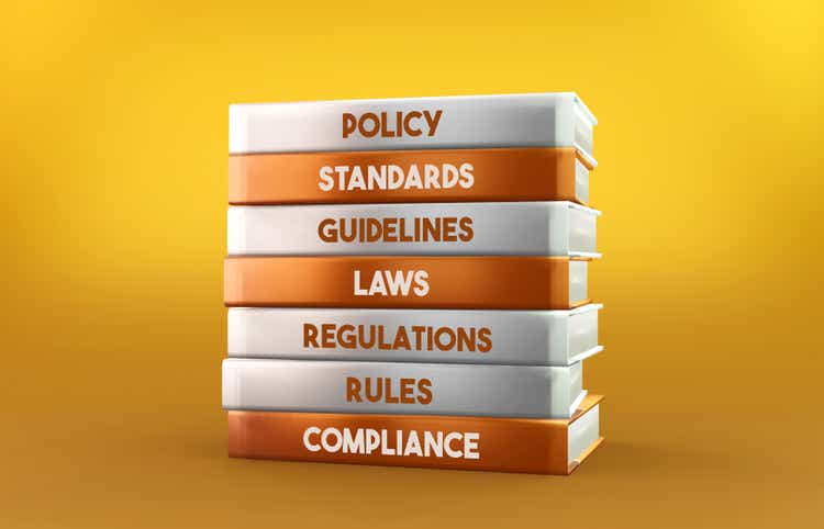 Orange und weiße Compliance-Bücher stehen auf orangefarbenem Hintergrund
