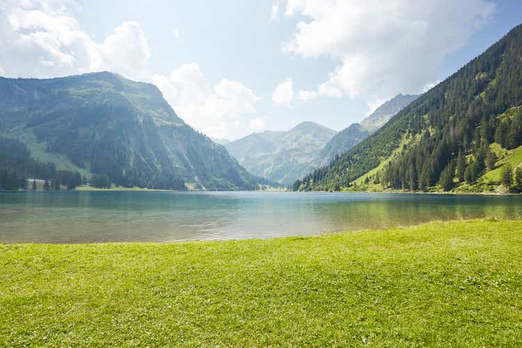 Grass pasture with lake and background mountains