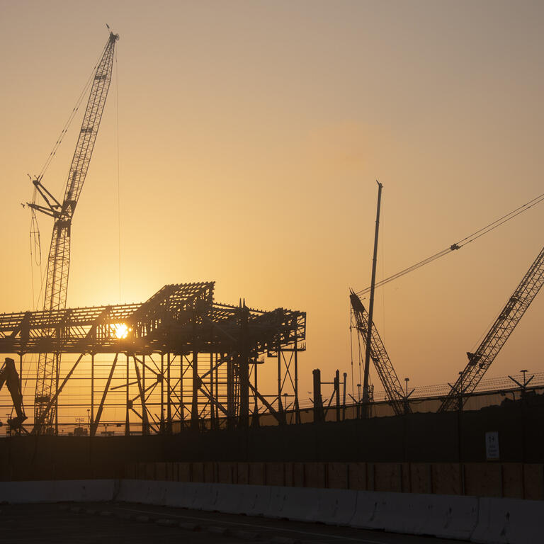 Steel frame of an airplane hangar being constructed at sunrise at LAX.