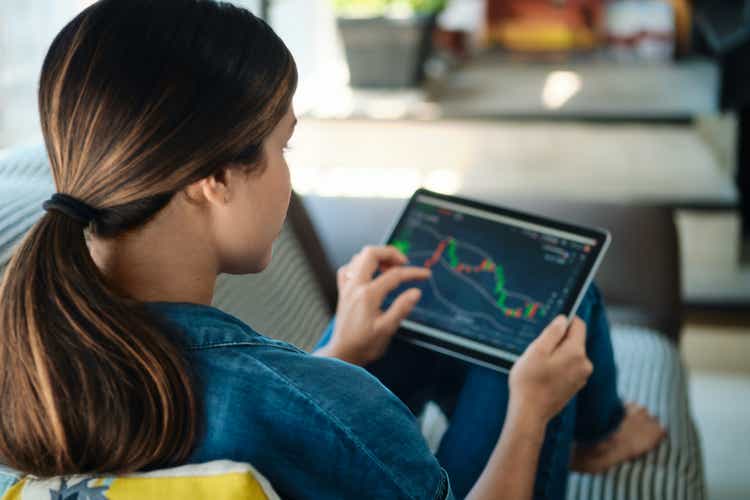 Woman Trading Online Using Tablet Computer On Sofa