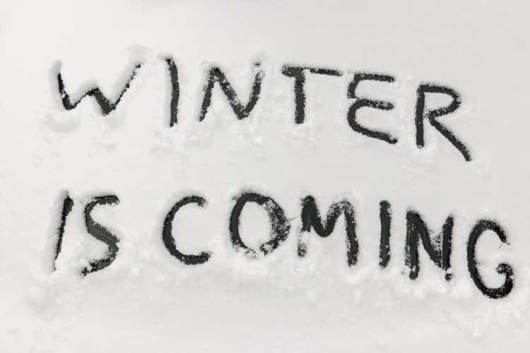 Word winter is coming scraped by hand on the frozen rear glass of car, auto glass covered with snow, cold winter season concept, first snowfall is a difficult weather for drivers and transport