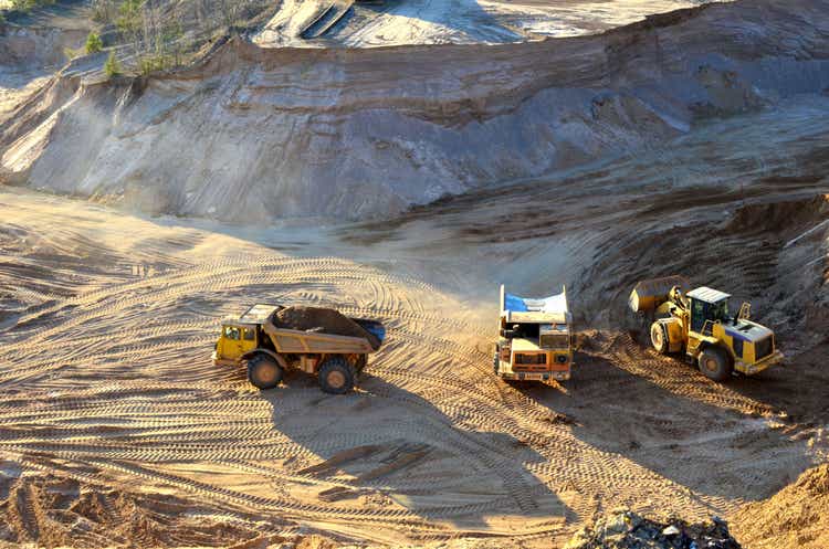 Wheel loader unloading sand into mining truck at the open pit