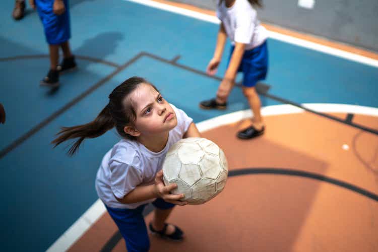 Focused student with disability playing basketball