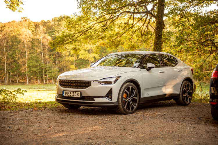 A white Polestar 2 by a park at fall..