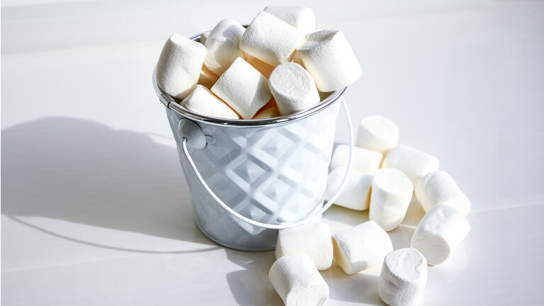 White mini marshmallows background close-up texture. Food background. Copy space. White metal bucket