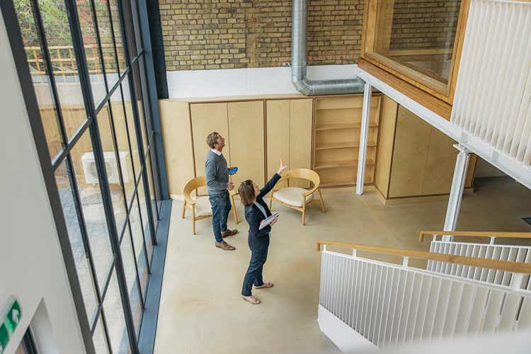 Female property agent showing man around empty office space