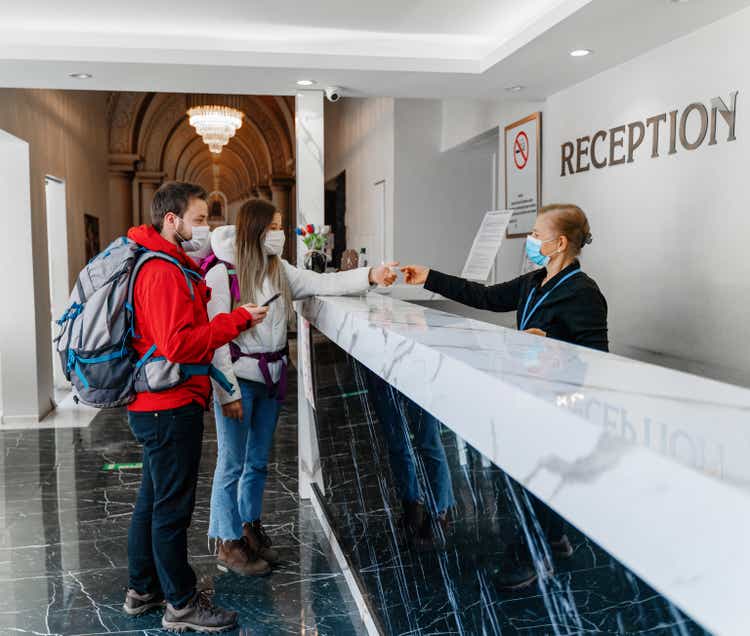 Couple wearing protective face mask while doing check-in at the hotel reception