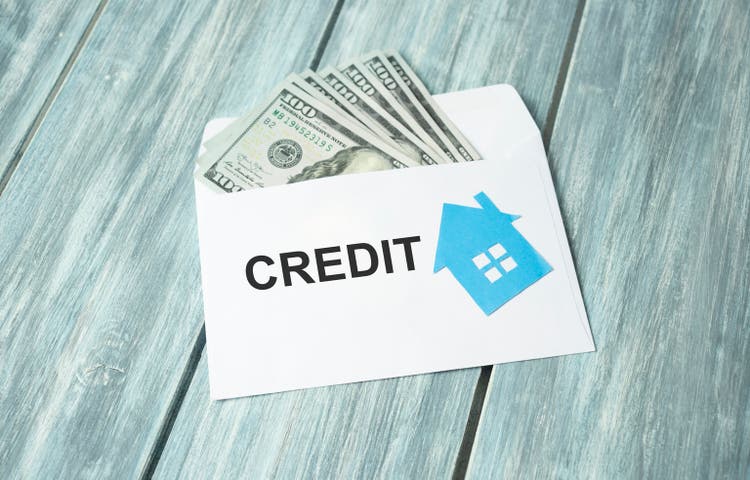 credit text on an envelope with money and a figurine of a house.