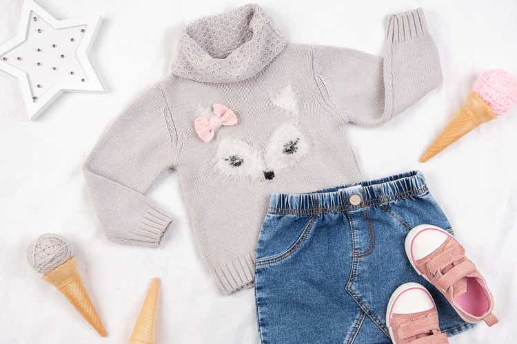 Set of casual child clothes, shoes and accessories on white background. Fashion girl lookbook consept. Knitted sweater, denim skirt, sneakers, ice cream cone. Top view, flat lay Closeup