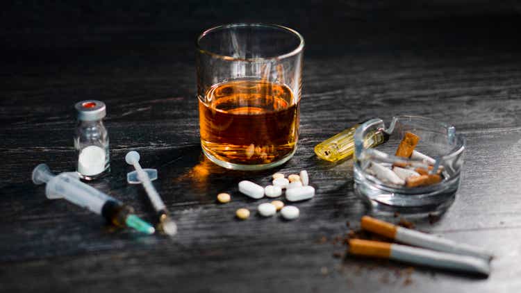 on wood table at party with alcohol and drugs or heroin, pills, gambling.