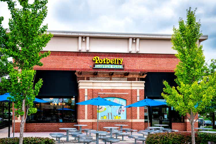 Outside empty seating area of Potbelly fast food restaurant with sign