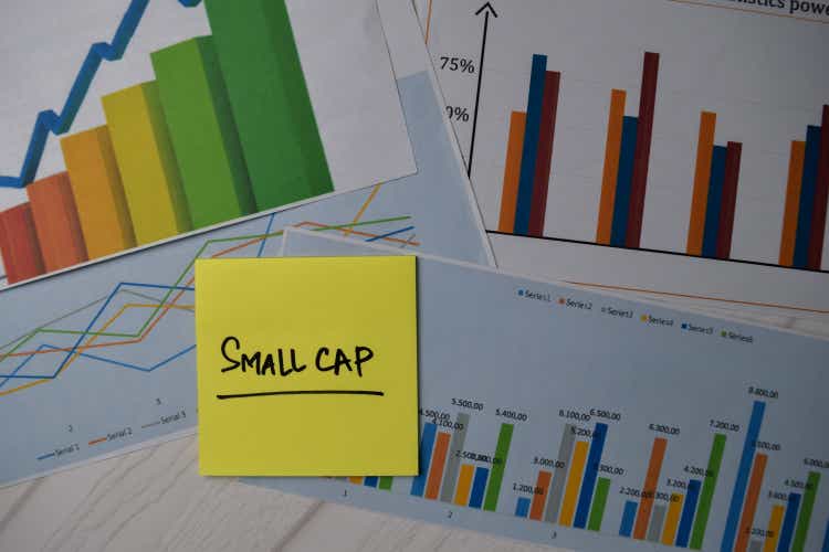 Little hat writes on sticky note isolated on office desk.  stock market concept