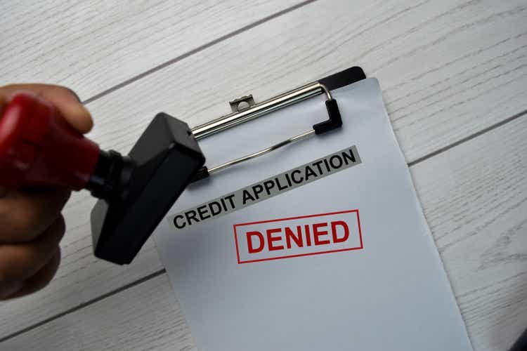 Red Handle Rubber Stamper and Credit Application - Denied text isolated on the table.