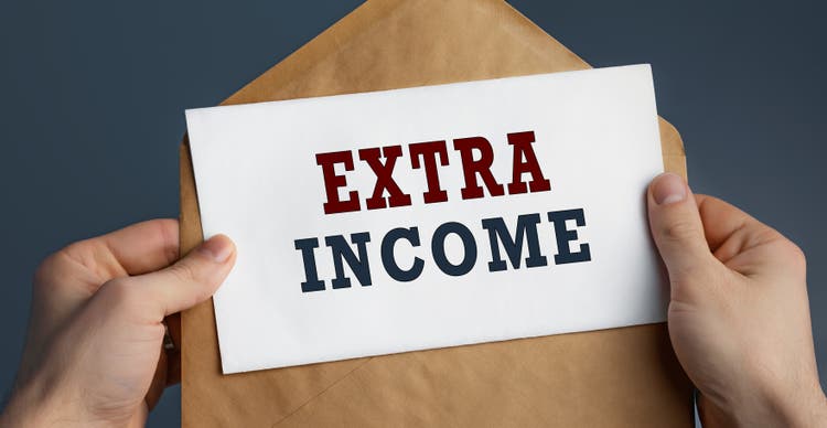 Male hands holding craft envelope with text EXTRA INCOME on blue background